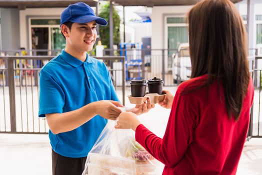 Asian young delivery man in blue uniform he making grocery service giving rice food boxes plastic bags to woman customer receiving front house under pandemic coronavirus, Back to new normal concept