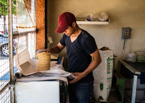 young man selling tortillas of nixtamal in typical mexican shop