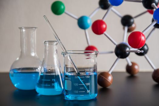 science laboratory beaker, erlenmeyer flask and molecule structure model, laboratory equipment concept