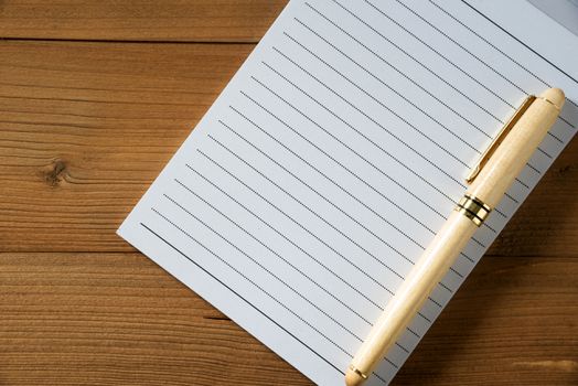 blank notebook with pen on brown wood table