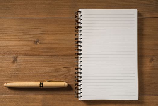 blank notebook with pen on brown wood table