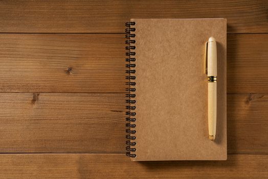 blank notebook with pen on brown wood table