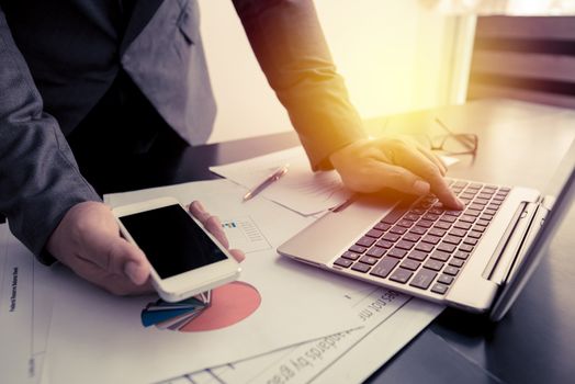 businessman working with smart phone and laptop on the work table, retro tone