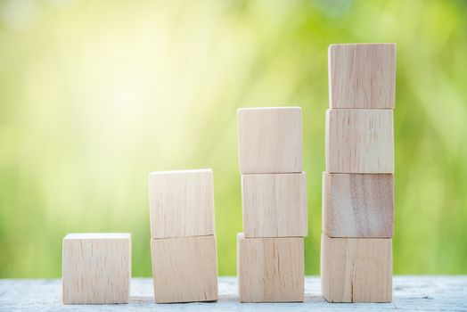 growing stack of wood cube on green natural background