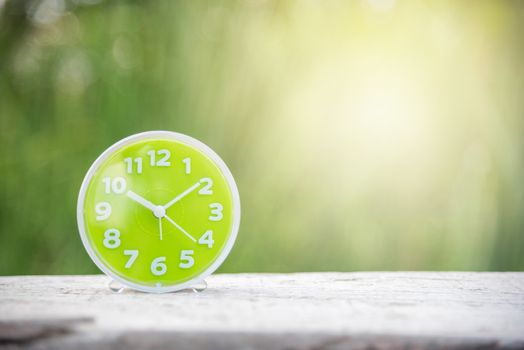 green clock on white wood and green natural background