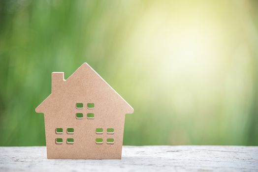 miniature wood house model on white wood and green natural background