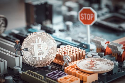 miniature people worker digging bitcoin on computer mainboard with stop sign , bitcoin concept