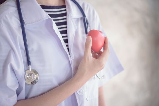 profressional woman doctor with green stethoscope and red heart in her hand