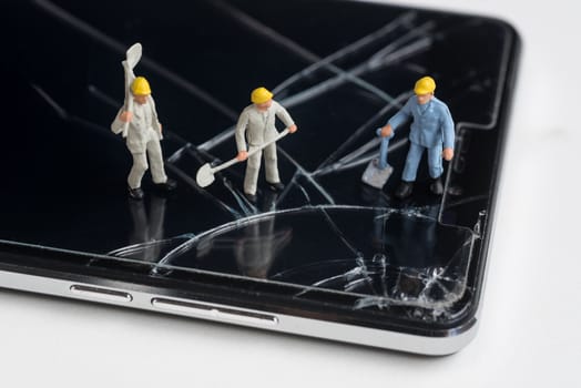 miniature worker working on cracked smartphone screen
