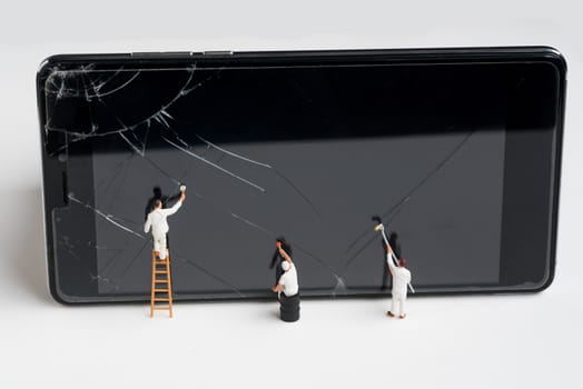 miniature people try to repair a cracked smart phone screen