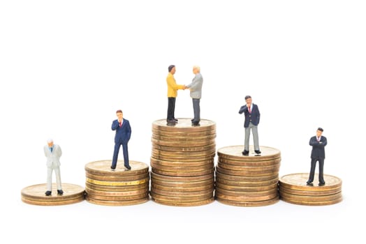 business miniature people shaking hand on stack of dollars coin