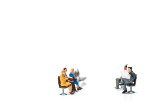 rows of miniature people figure sitting on bench white background