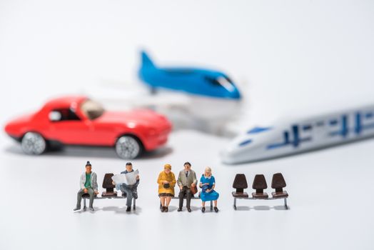 row of miniature people figure sitting on bench with air plane,car,hispeed train model figure background