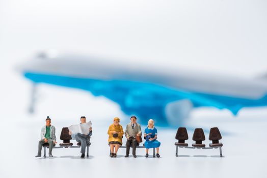 row of miniature people figure sitting on bench with air plane model figure background