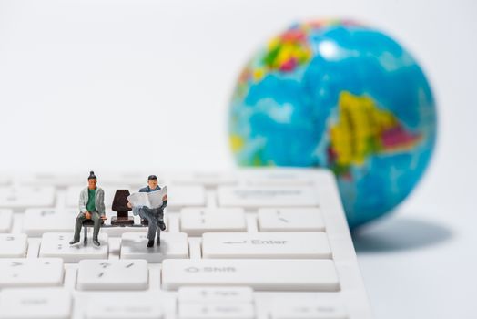miniature people figure sitting on bench with globe figure  background