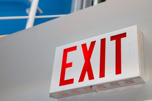 A perspective view from a low angle showing a red "EXIT" sign on a white wall.