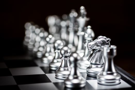 silver chess pieces on a chessboard, business strategy concept