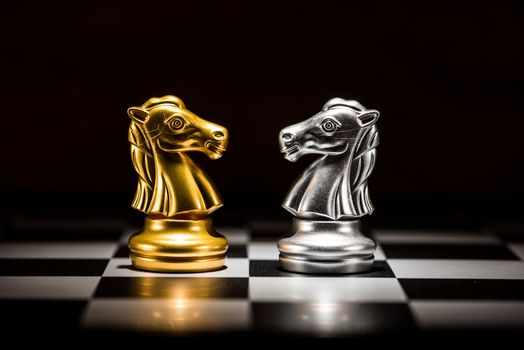 gold knight chess facing silver knight chess on chess board , business strategy concept