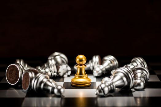 single gold pawn chess surrounded by a number of fallen silver chess pieces , business strategy concept