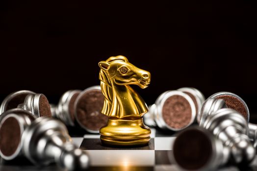 gold knight chess surrounded by a number of fallen silver chess pieces , business strategy concept