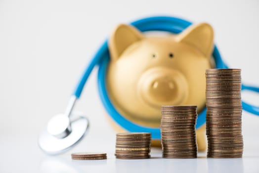 piggy bank with stethoscope and coins stack on white background.