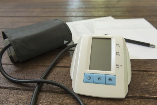 Digital blood pressure monitor on a wood table.