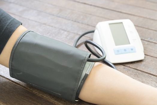 Woman checking blood pressure and heart rate with a digital blood pressure monitor.