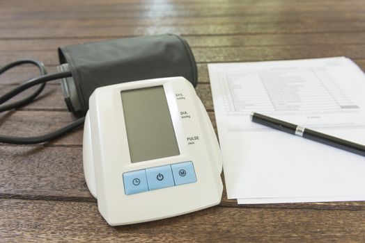 Digital blood pressure monitor on a wood table.