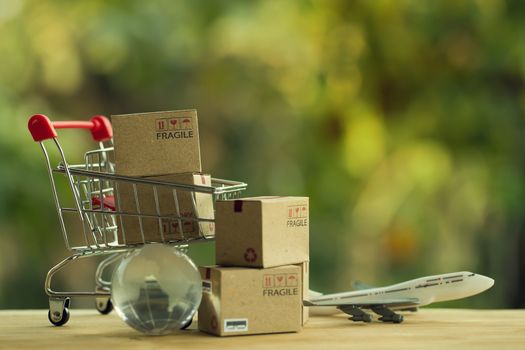 Shopping Online and e-commerce concept: Paper boxes in a shopping cart and crystal globe, plane. Online stores are considered as another medium of trading goods between entrepreneurs and customers.