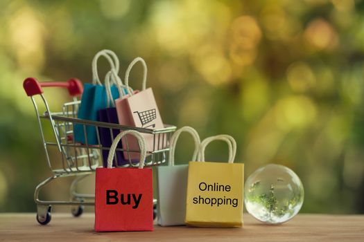 Shopping Online and e-commerce concept: Paper bag in a shopping cart and crystal globe. Online stores are considered as another medium of trading goods between entrepreneurs and customers.