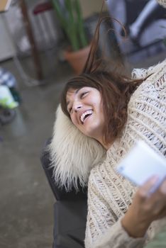 Portrait of smiling nice woman using cellphone while lying on sofa