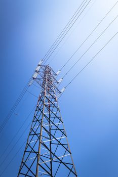 Overhead power line and a pylon against the blue sky