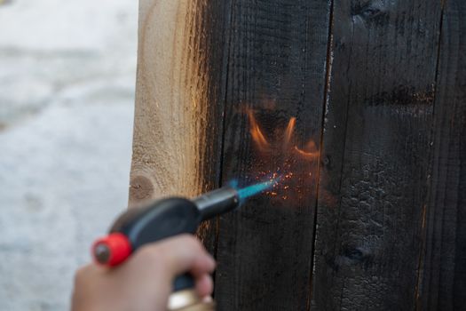 Professional carpenter using old traditional japanese technique. Burning wood planks with gas burner. DIY process.