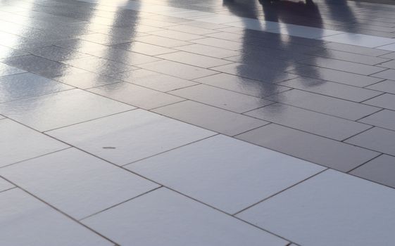 Diffuse reflections of pedestrians walking a marble sidewalk