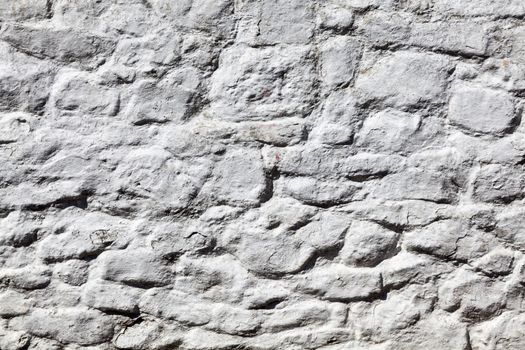 Old grey white weathered rough stone wall texture background