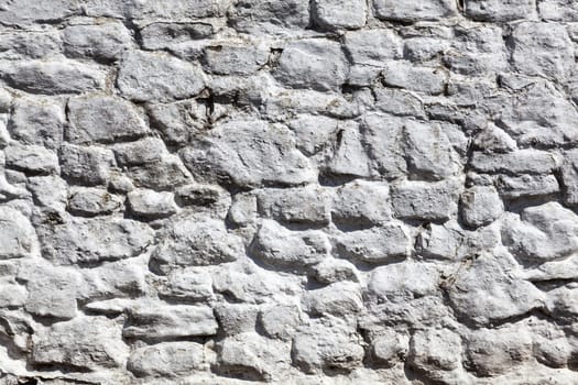 Old grey white weathered rough stone wall texture background