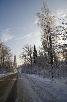 Winter view of the ancient church and bell tower in the Russian village Avdotieno, surrounded by frozen trees