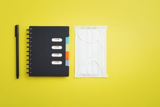 Hygiene face mask with office supply as notebook and a pen for new normal or new way of living concept