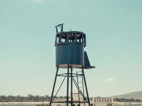 An old army guard metallic watchtower. In Kibbutz Degania, Israel. Banana plantation in the background and blue sky. Summer sunny day.