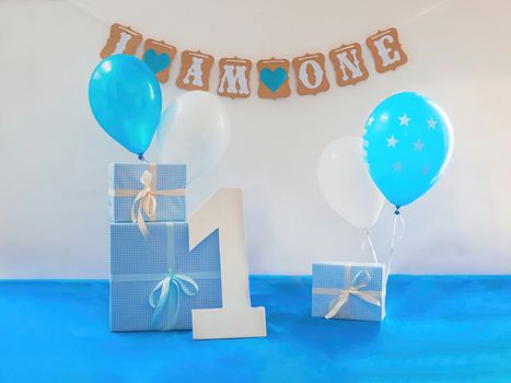 One year birthday decorations set. Decoration for a boy holiday party. Bunch of blue & white balloons, gift boxes, large white kappa board number one shape, and sign with the inscription "I am one".