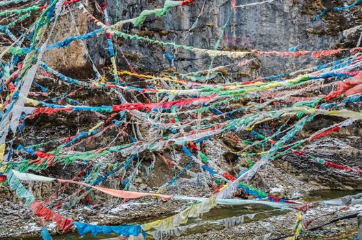 Colorful prayer flags are waving above the river at a mountain pass near Golog city