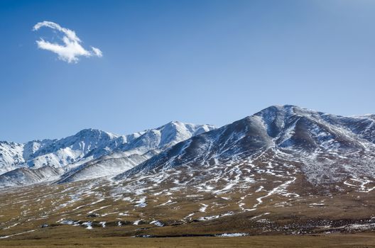 Beautiful snowy Tibetan high mountain landscape at Qinghai province with the lonely cloud on a blue sky