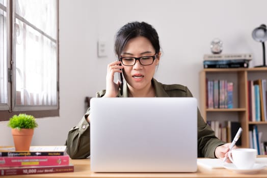 Modern young Asian woman working from home and talking with a partner about her business.