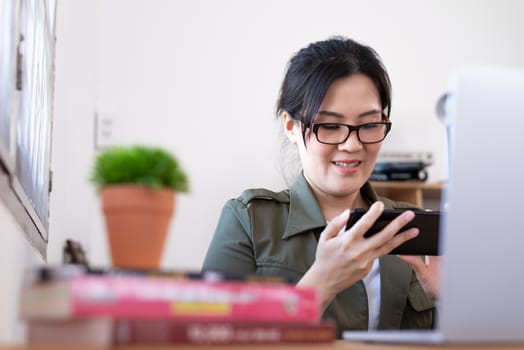 Modern young Asian woman playing a game instead of working from home with happy and fun.