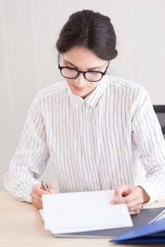 A businesswoman wearing glasses working with smiling and happiness at the office.