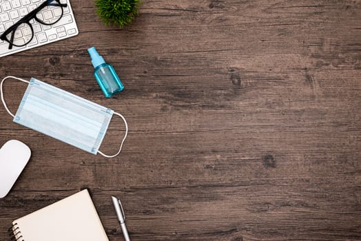 The equipment to protect COVID-19, blue mask and hand cleaner gel for preparing to work from home Isolated on wood desk.