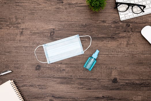 The equipment to protect COVID-19, blue mask and hand cleaner gel for preparing to work from home Isolated on wood desk.