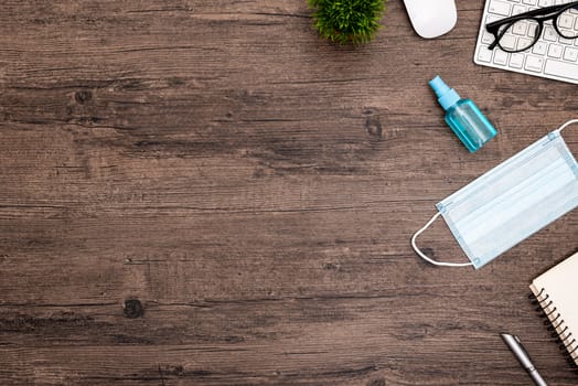 The equipment to protect COVID-19, blue mask and hand cleaner gel for preparing to work from home Isolated on wood desk.