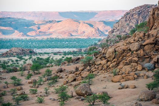 Rocky landscape of Kunene Region at Namibian winter with huge boulders and green trees