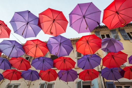 Colorful decorative umbrellas hanging between houses of a street